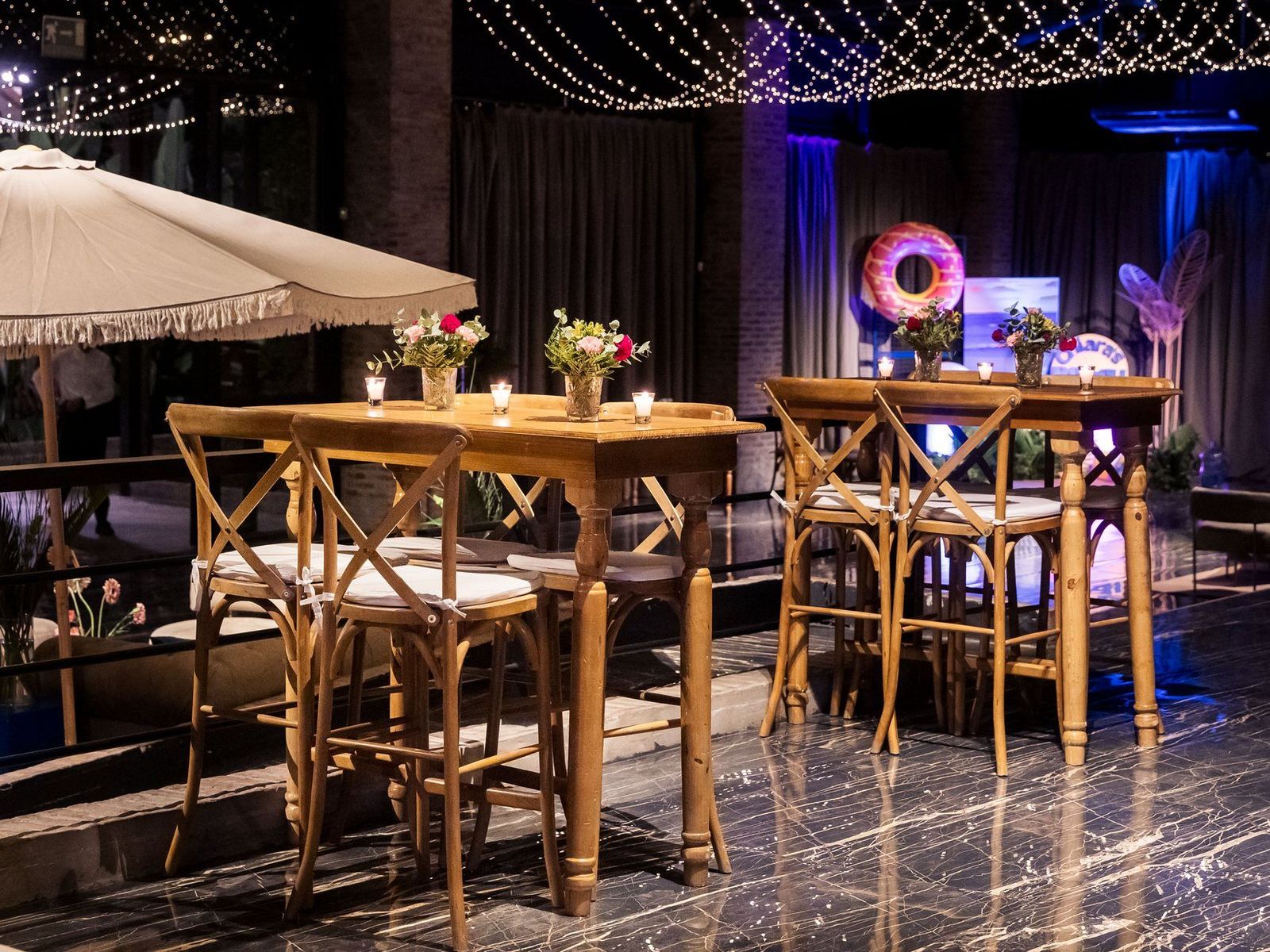 Recepción de Bayres Eventos con mesas altas, flores y guirnaldas de luces